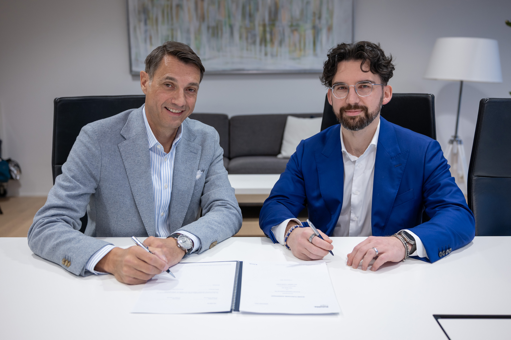 Patrick Fruth (left), CEO of the Mobility Division at TÜV SÜD, and Rafael Osmanov, founder of Helix Partners, sign the purchase agreement.