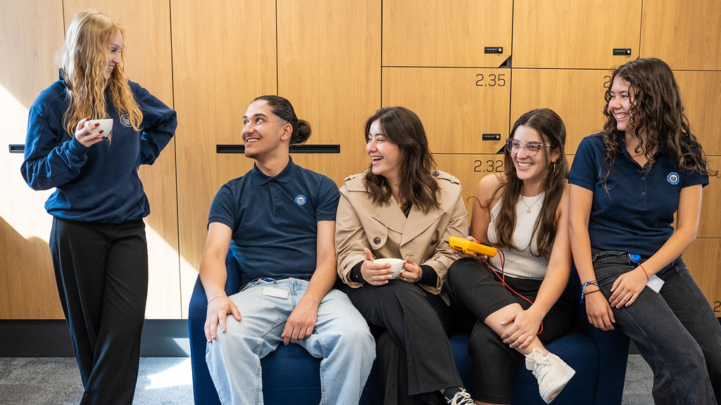 A group of young people chilling on a sofa in an office environment, talking and laughing.