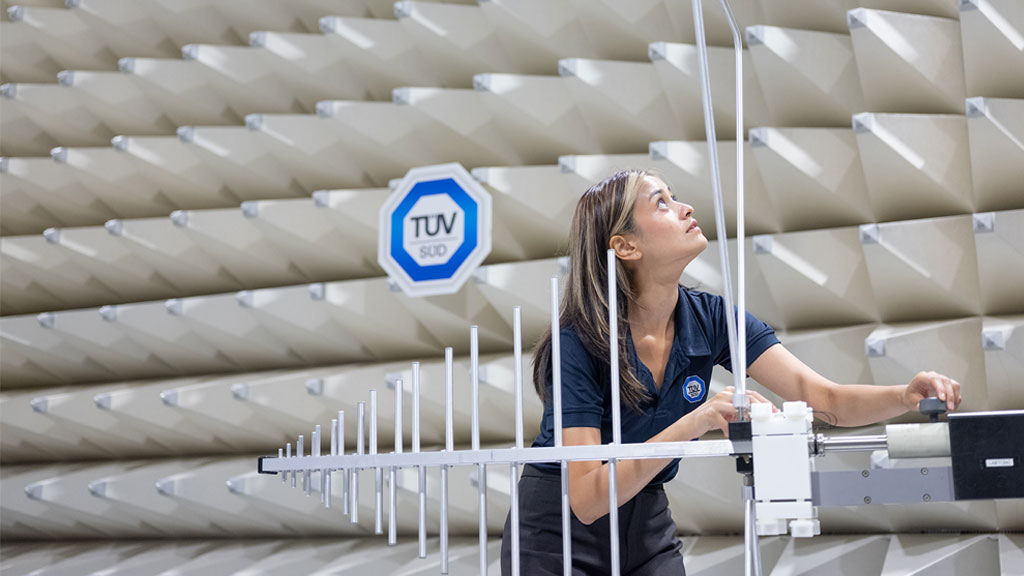 A person operates equipment with multiple antenna elements in an anechoic chamber with sound-absorbing panels on the walls.