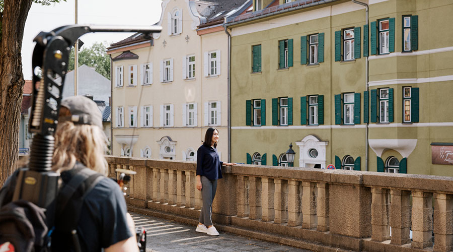An Asian woman is filmed by a cameraman in an urban environment
