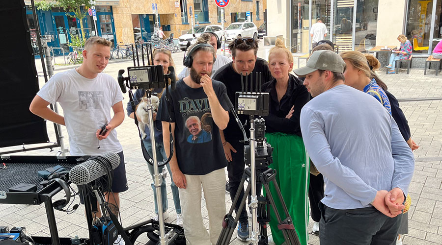 Film crew standing on a street watching the footage they have just filmed