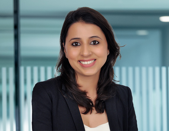 A woman in a dark blazer over a white shirt, smiling into the camera.
