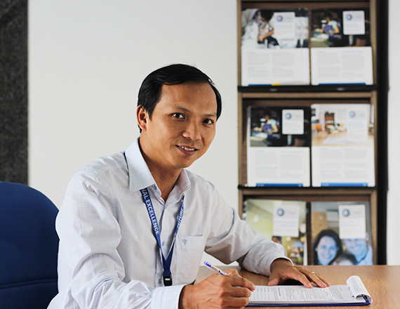 Tran Minh Tai: An Asian man sits at his desk in the office.