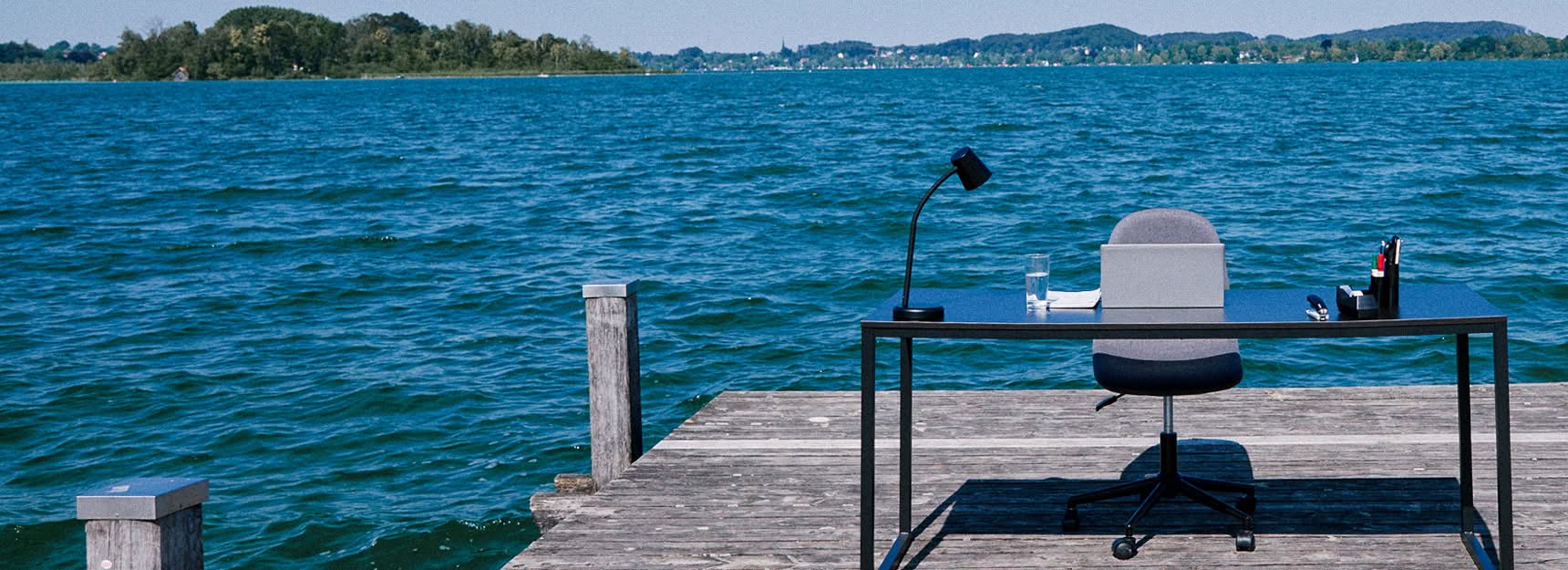A desk and chair on a pier in a Bavarian lake.