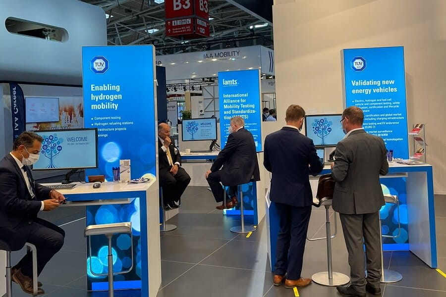 Menschen stehen um Stände auf einer Messe und unterhalten sich.