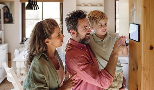 Dreiköpfige Familie steht an einem digitalen Bediendisplay
