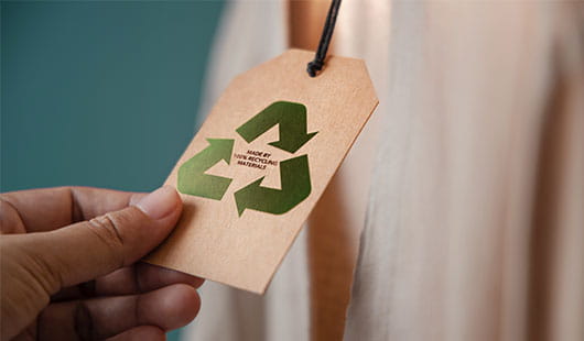 Hand hält Anhängeetikett das das Recycling-Symbol trägt