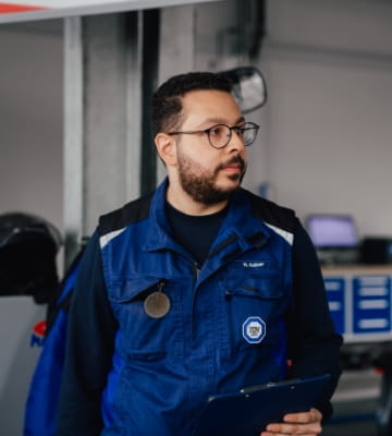 Kfz-Prüfingenieur in Arbeitskleidung mit Tablet in der Hand