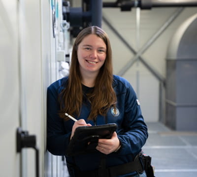 TGA Ingenieurin mit Tablet im Technik-Raum