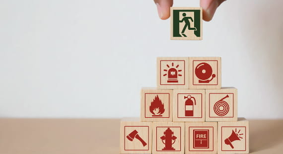 Gestapelte Holzwürfel, die Brandschutzsymbole tragen.