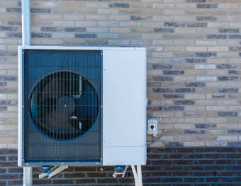 Wärmepumpe steht vor einer Hauswand
