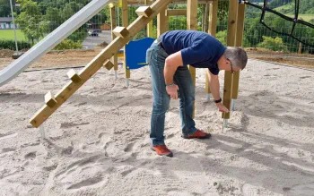 Spielplatzprüfer prüft Untergrund von Spielplatz