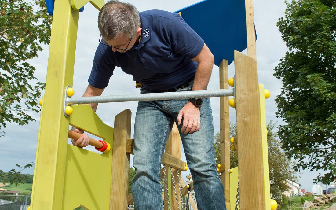 Spielplatzprüfer prüft Spielgerät auf Spielplatz