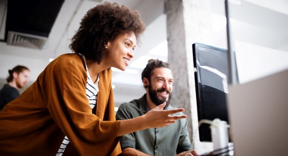 Zwei Mitarbeitende arbeiten gemeinsam an einem Computer im modernen Büro.