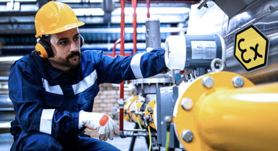 Ein Industriearbeiter inspiziert ein Rohrleitungssystem in einer industriellen explosiven Umgebung als Symbol für Explosionsschutz