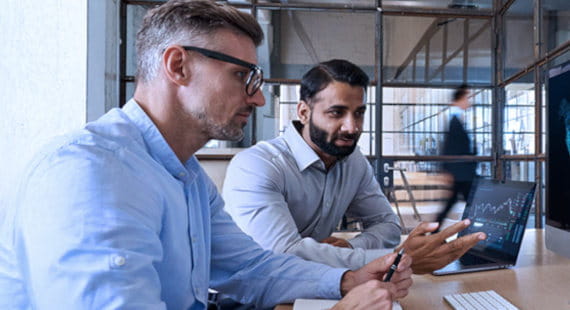 Zwei Geschäftspartner vor einem Bildschirm im Büro als Symbol für Global Market Access