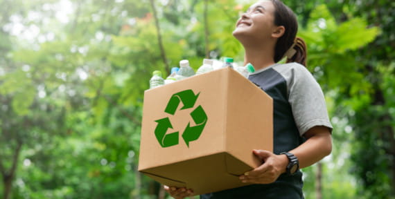 Mädchen mit Karton voller Plastikflaschen