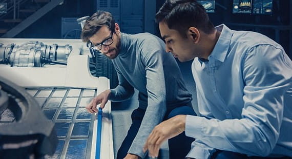 Zwei Ingenieure diskutieren über Batteriesicherheit in einer hochmodernen Fabrikumgebung.