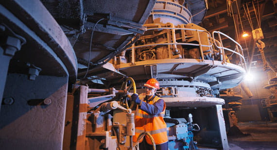 Mann in orangener Warnweste und Helm in Fabrik