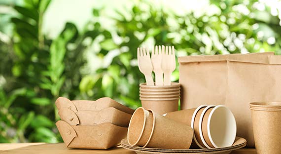 Ustensiles et emballages écologiques en matériaux durables devant un fond naturel