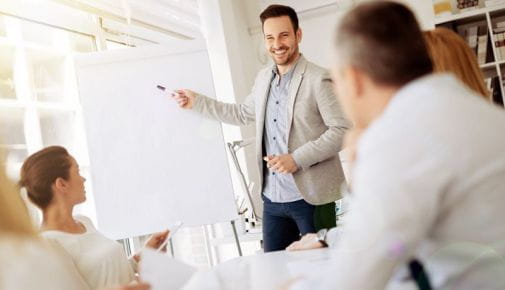 Formador explicando en una pizarra a un grupo de personas