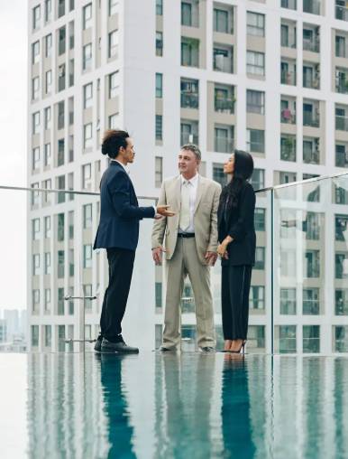Trois personnes en discussion sur une terrasse avec des immeubles en arrière-plan