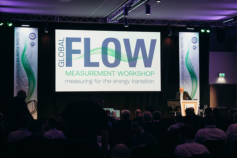 stage with global flow measurement workshop banner and man standing at lectern