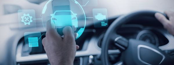 A person is seated in a car, using the dashboard controls to manage various functions while driving.
