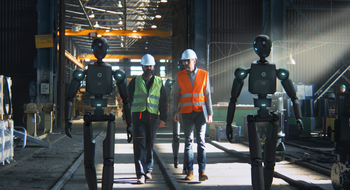 2 Arbeiter mit Warnwesten und Helm und 2 lebensgro&szlig;e Roboter