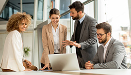 4 Personen diskutieren vor einem Laptop